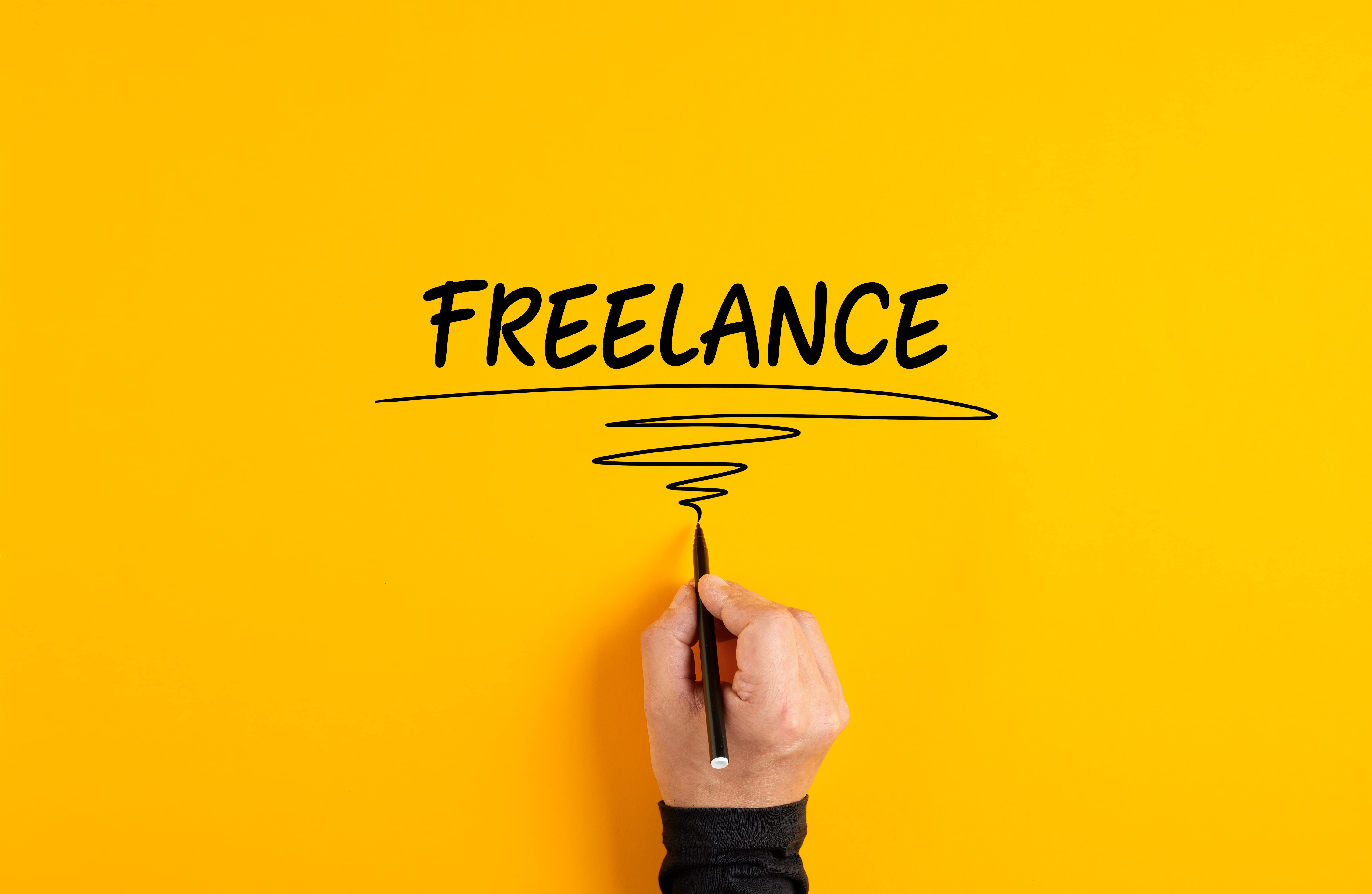 Learn how you can start a business from scratch with zero capital. Image shows a hand that's against a yellow background that has just written the word freelance on the background.