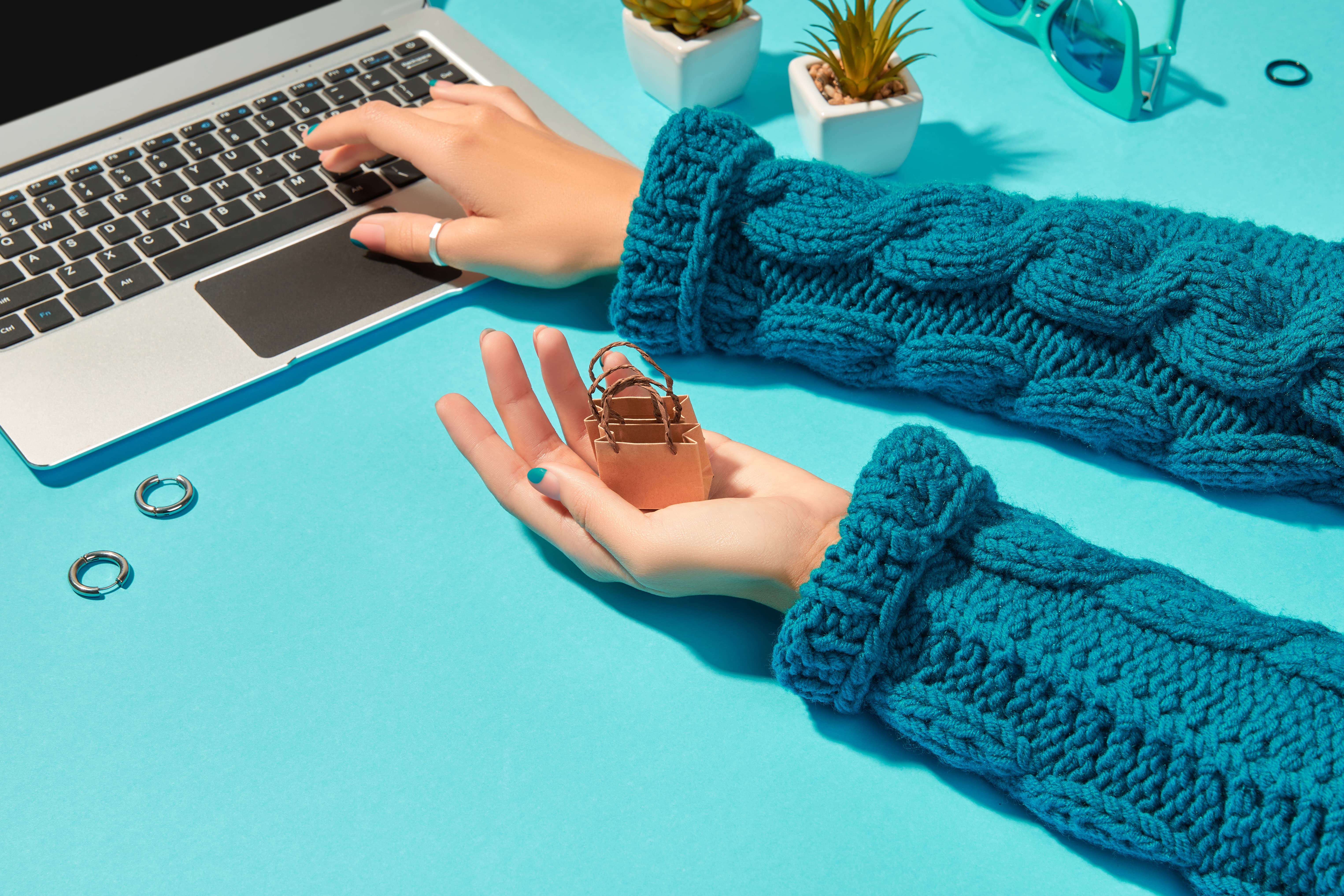 Image shows a woman making a purchase online with earrings near the laptop indicating she's buying jewellery.